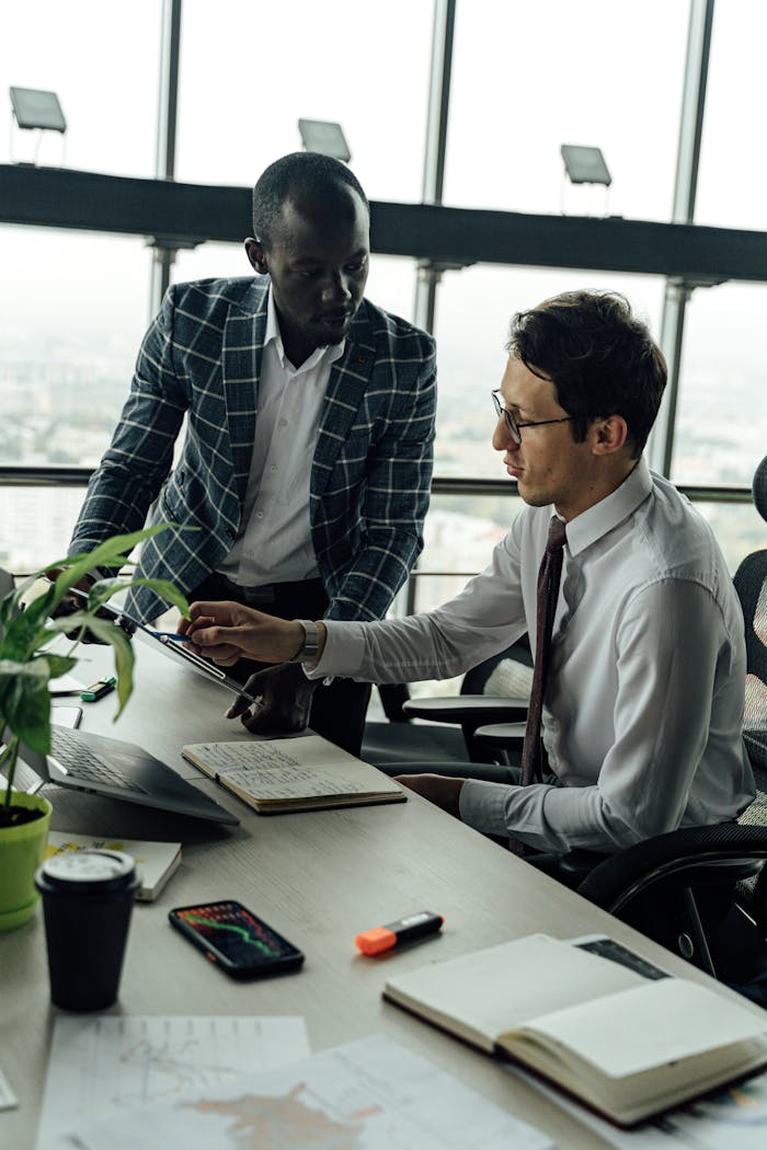 services-02 Two businessmen discussing projects in a modern high-rise office setting.